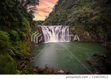 Large waterfall at sunset 110034421