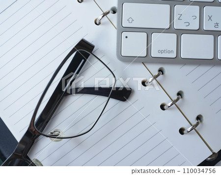 Notebook, glasses and keyboard placed on the table 110034756