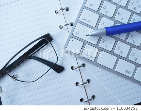 Notebook, glasses and keyboard placed on the table 110034758