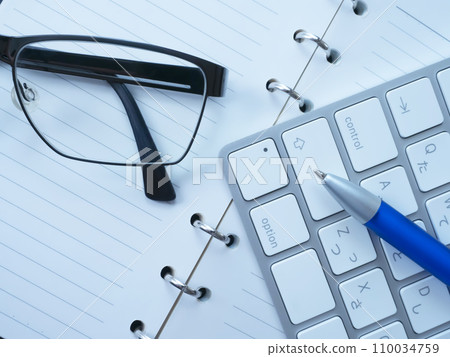 Notebook, glasses and keyboard placed on the table 110034759