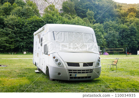 Motor home standing on a meadow near the forest and mountains. 110034935