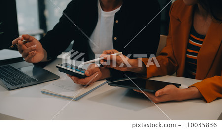 Charming Young asian businesswoman sitting on laptop computer in the office, making report calculating balance Internal Revenue Service checking document. 110035836