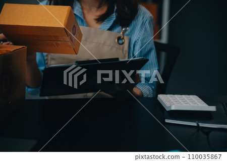 Startup small business entrepreneur or freelance Asian woman using a laptop with box, Young success Asian woman with her hand lift up, online marketing packaging box and delivery, SME concept. 110035867