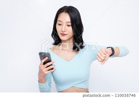 There is a woman wearing a watch and looking at her phone 110038746