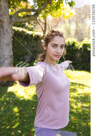 Portrait of happy biracial woman practicing yoga standing stretching in sunny garden, copy space Portrait of happy biracial woman practicing yoga standing stretching in sunny garden, copy space 110039298