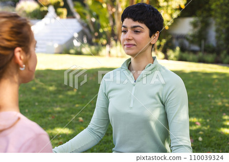 Happy biracial lesbian couple practicing yoga meditation sitting stretching in sunny garden 110039324