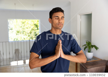Biracial man doing yoga and meditating at home Biracial man doing yoga and meditating at home 110039432