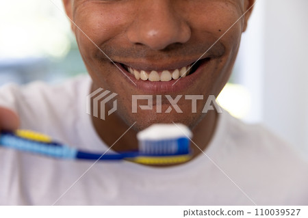 Happy biracial man holding toothbrush in bathroom at home 110039527