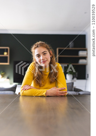 Smiling biracial woman sitting at dining table having video call at home, listening, copy space 110039529