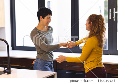 Happy biracial lesbian couple having fun dancing in kitchen 110039581