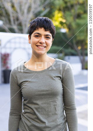 Portrait of happy biracial woman with short dark hair standing on garden terrace smiling Portrait of happy biracial woman with short dark hair standing on garden terrace smiling 110039597