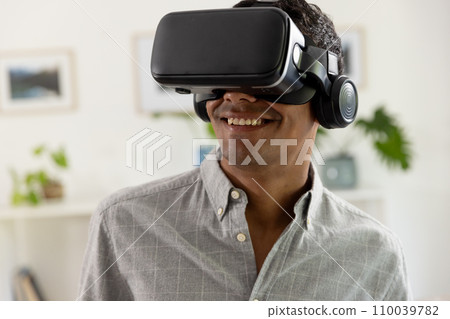 Happy biracial man using vr headset at home Happy biracial man using vr headset at home 110039782