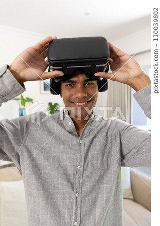 Portrait of happy biracial man using vr headset at home 110039802