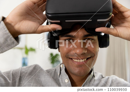 Portrait of happy biracial man using vr headset at home 110039930