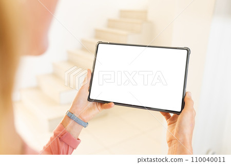 Happy blonde caucasian woman using tablet with copy space in sunny living room at home Happy blonde caucasian woman using tablet with copy space in sunny living room at home 110040011