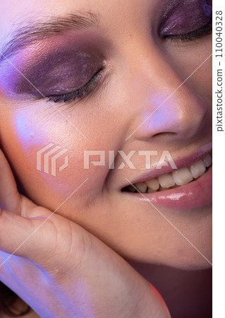 Close up of caucasian woman wearing purple eye shadow 110040328