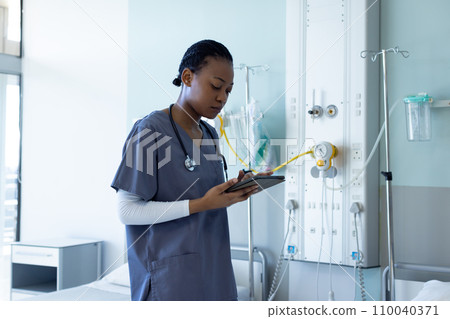 African american female doctor using tablet in hospital room 110040371