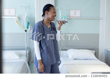 Happy african american female doctor talking on smartphone in hospital room 110040403