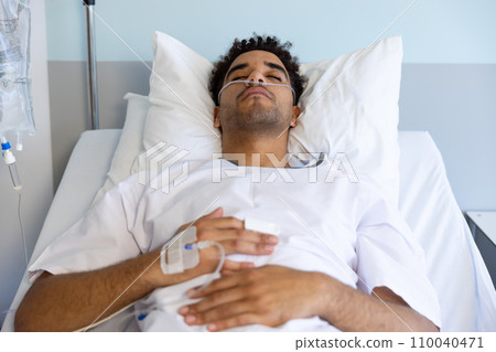 Biracial male patient sleeping in bed in sunny hospital room 110040471
