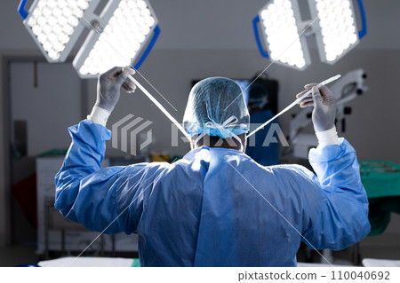 Back of african american female doctor wearing face mask in hospital operating room Back of african american female doctor wearing face mask in hospital operating room 110040692