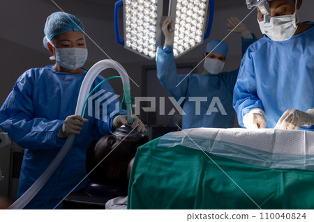 Diverse female doctors with face masks doing surgery in hospital operating room 110040824