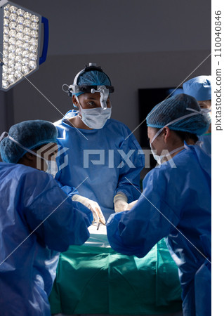 Diverse female doctors with face masks doing surgery in hospital operating room 110040846