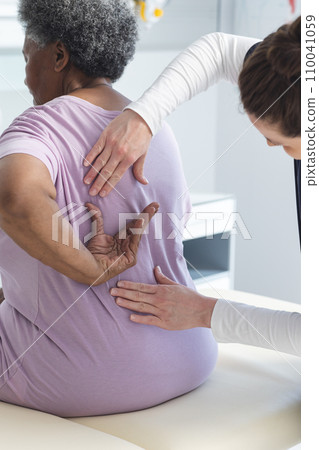 Diverse female doctor testing back of senior female patient in hospital room Diverse female doctor testing back of senior female patient in hospital room 110041059