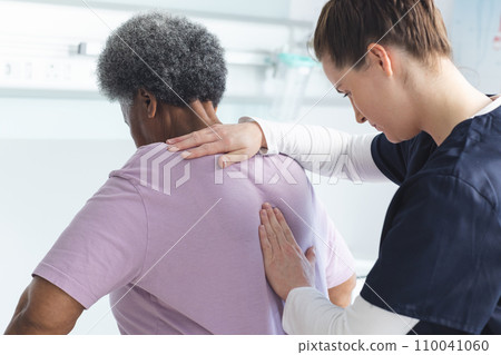 Diverse female doctor testing back of senior female patient in hospital room Diverse female doctor testing back of senior female patient in hospital room 110041060
