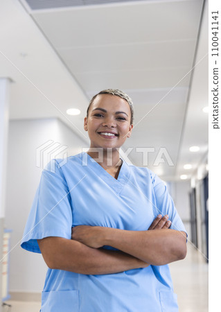 Portrait of happy biracial female doctor wearing scrubs in corridor at hospital, copy space Portrait of happy biracial female doctor wearing scrubs in corridor at hospital, copy space 110041141