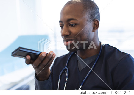 African american male doctor talking on smartphone at desk in hospital 110041265