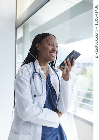 Happy african american female doctor talking on smartphone in hospital room Happy african american female doctor talking on smartphone in hospital room 110041436