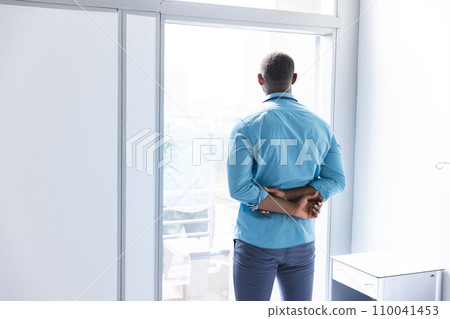 Thoughtful african american male doctor looking through window in hospital room, copy space Thoughtful african american male doctor looking through window in hospital room, copy space 110041453