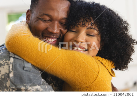 Happy african american male soldier embracing wife at home Happy african american male soldier embracing wife at home 110042001