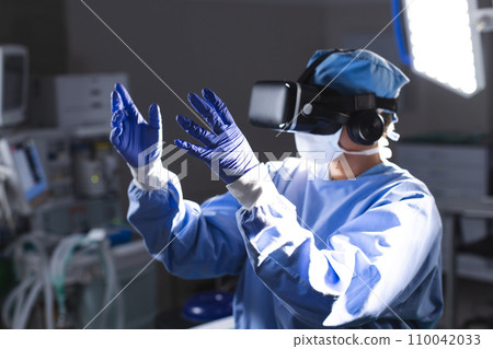 Biracial female surgeon wearing surgical gown using vr headset in operating theatre Biracial female surgeon wearing surgical gown using vr headset in operating theatre 110042033