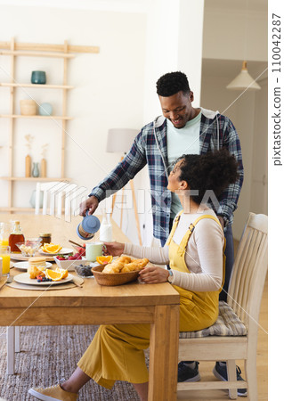 African american man pouring tea to cup at breakfast in morning at home, copy space African american man pouring tea to cup at breakfast in morning at home, copy space 110042287