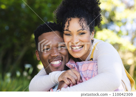 Happy african american couple embracing in sunny garden, copy space Happy african american couple embracing in sunny garden, copy space 110042309