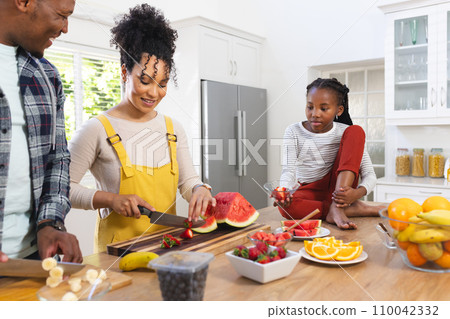 Happy african american family preparing fresh snack from fruits in kitchen at home, copy space Happy african american family preparing fresh snack from fruits in kitchen at home, copy space 110042332