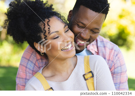 Happy african american couple embracing in sunny garden, copy space Happy african american couple embracing in sunny garden, copy space 110042334