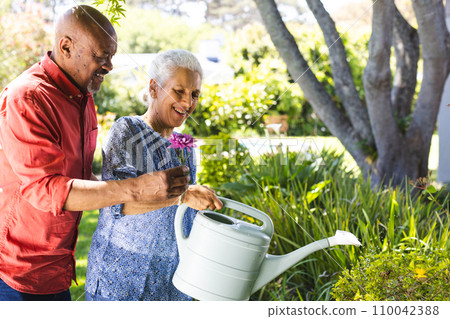 Happy diverse senior couple gardening in sunny garden Happy diverse senior couple gardening in sunny garden 110042388