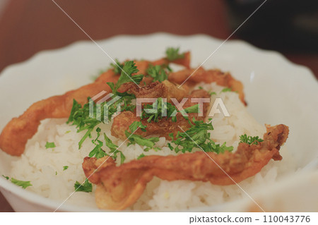 A bowl of rice topped with crispy fried chicken skin chicharon or crackling and fresh parsley, Filipino local delicacy A bowl of rice topped with crispy fried chicken skin chicharon or crackling and fresh parsley, Filipino local delicacy 110043776