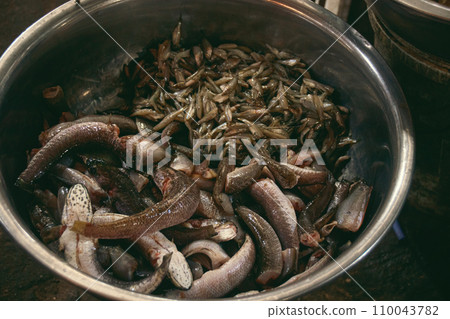 A metal bowl filled with fresh raw seafood in the local traditional Samaki wet market in Kampot Cambodia, authentic candid moment of khmer daily life and culture  110043782