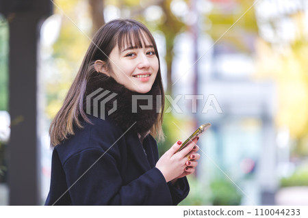 一個操作智能手機的年輕女子 一個操作智能手機的年輕女子 110044233