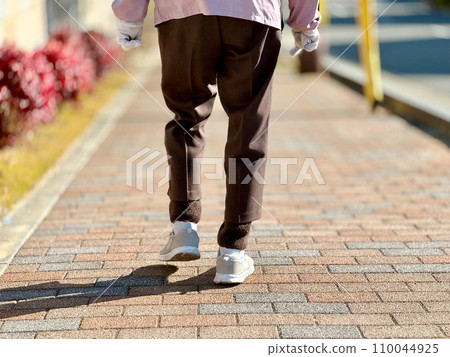 The feet of an elderly woman walking on the sidewalk in a residential area The feet of an elderly woman walking on the sidewalk in a residential area 110044925