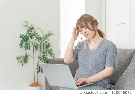 Pregnant woman/maternity/premum working on a computer on the sofa at home Pregnant woman/maternity/premum working on a computer on the sofa at home 110046072
