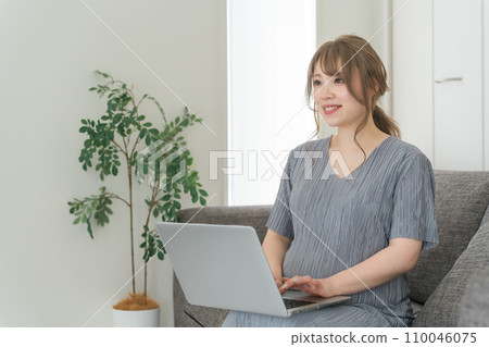 Pregnant woman/maternity/premum working on a computer on the sofa at home Pregnant woman/maternity/premum working on a computer on the sofa at home 110046075