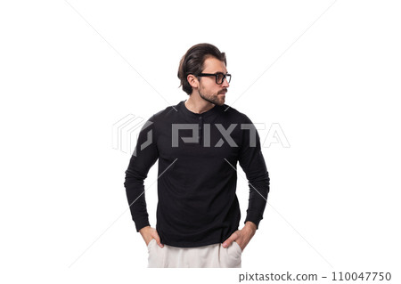 brutal young brunette man with a beard in a black turtleneck put on glasses for vision correction 110047750