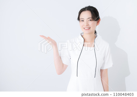 The upper body of a young female beauty or medical nurse in a white nurse's uniform who guides you towards this direction. 110048403