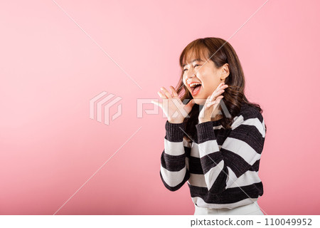 Portrait of a triumphant Asian woman with raised fists, celebrating her win and saying yes with a joyful expression. Studio shot isolated on pink. 110049952
