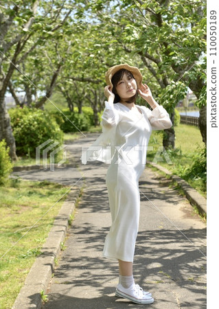 Fresh green park and young woman wearing a straw hat Fresh green park and young woman wearing a straw hat 110050189
