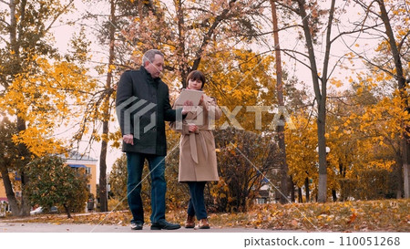 Male manager explains plan for promoting company to female employee on tablet 110051268